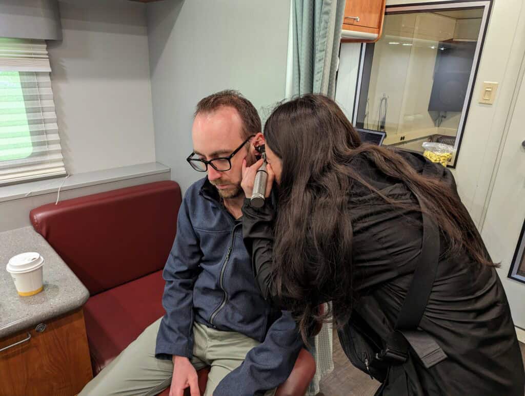 student at Central Michigan University checks the ears of a HLAA Walk4Hearing event attendee