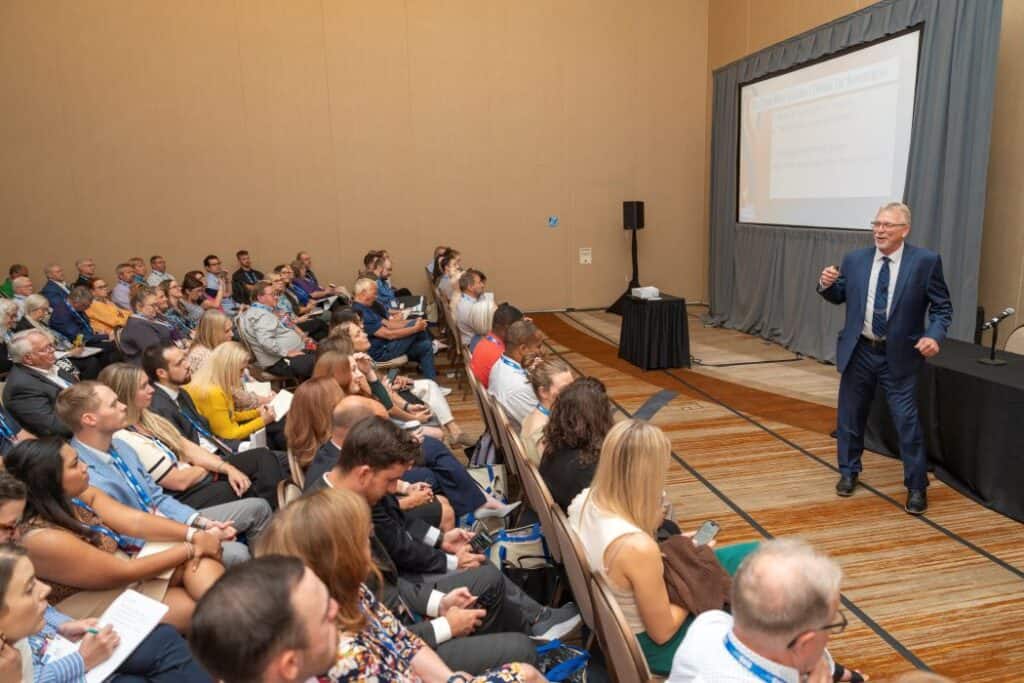 speaker presenting in front of a large audience at the IHS Conference & Expo