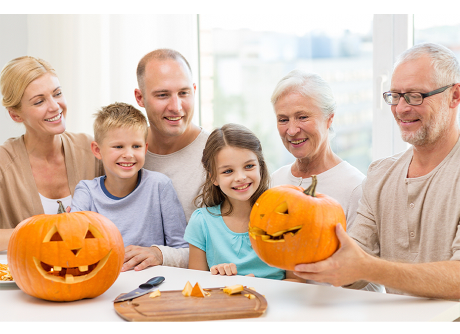 Family carving pumpkins for Halloween, smiling and happy.