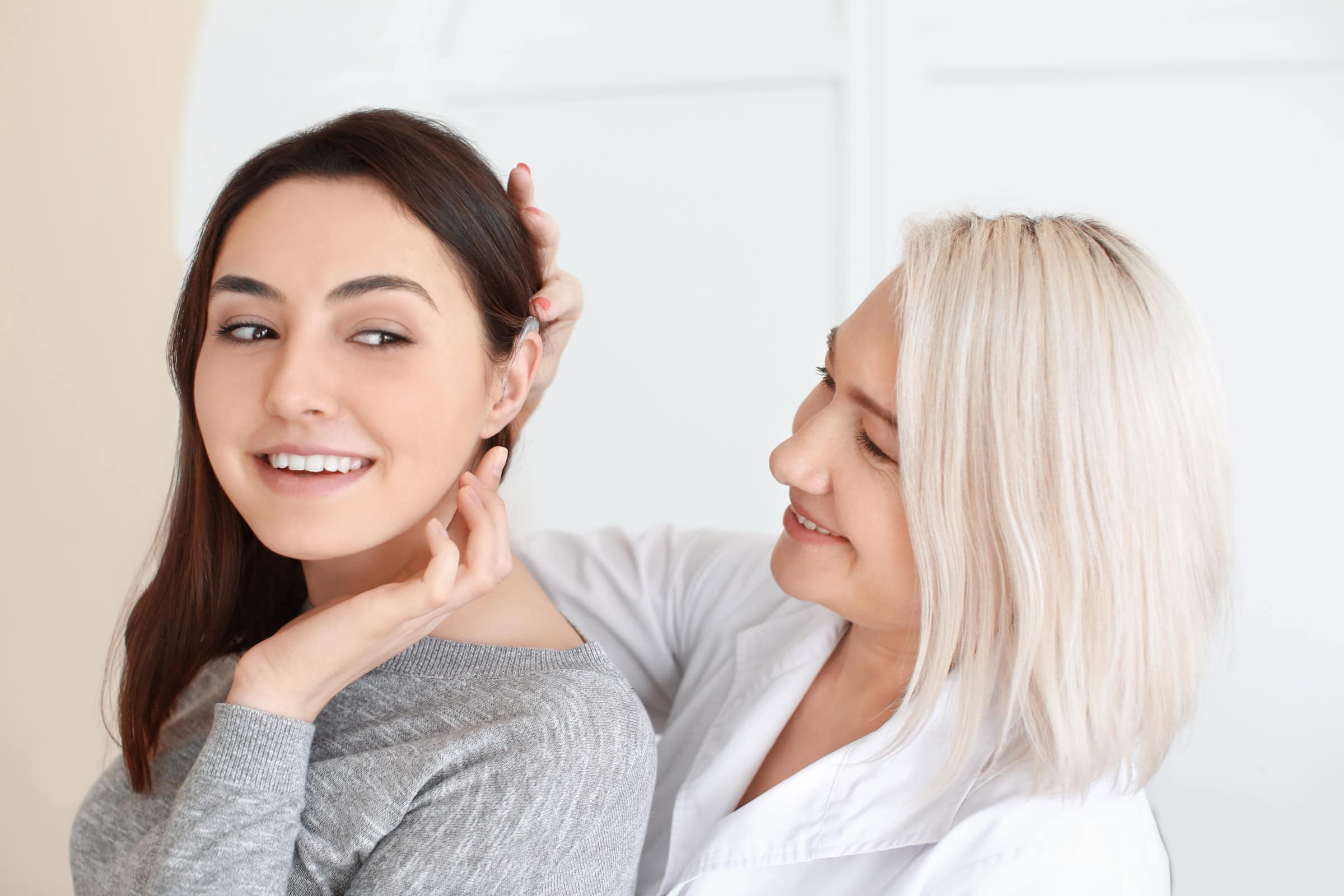 An older woman checking a young woman's ear in a clinical setting.
