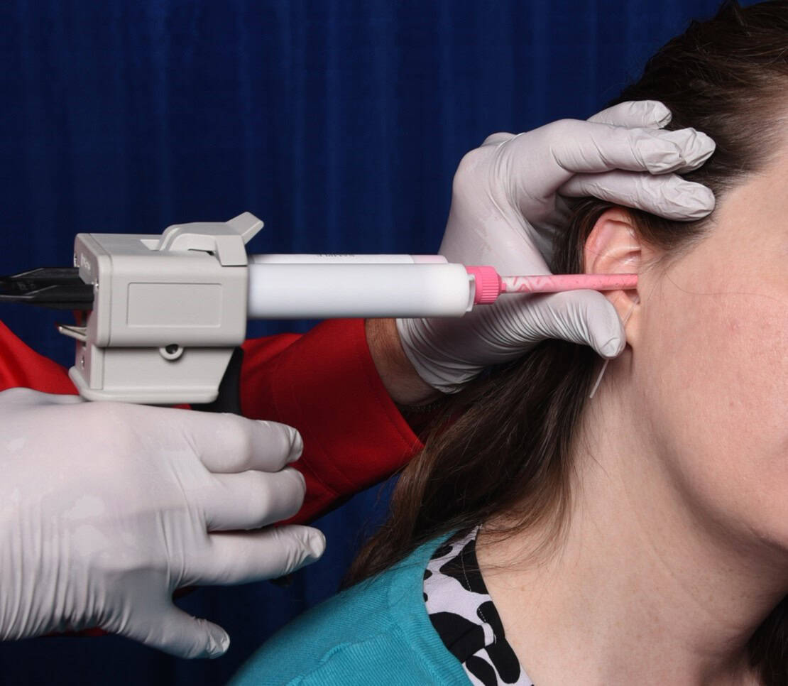 Medical professional performing bridge-and-brace technique on patient’s neck with syringe.
