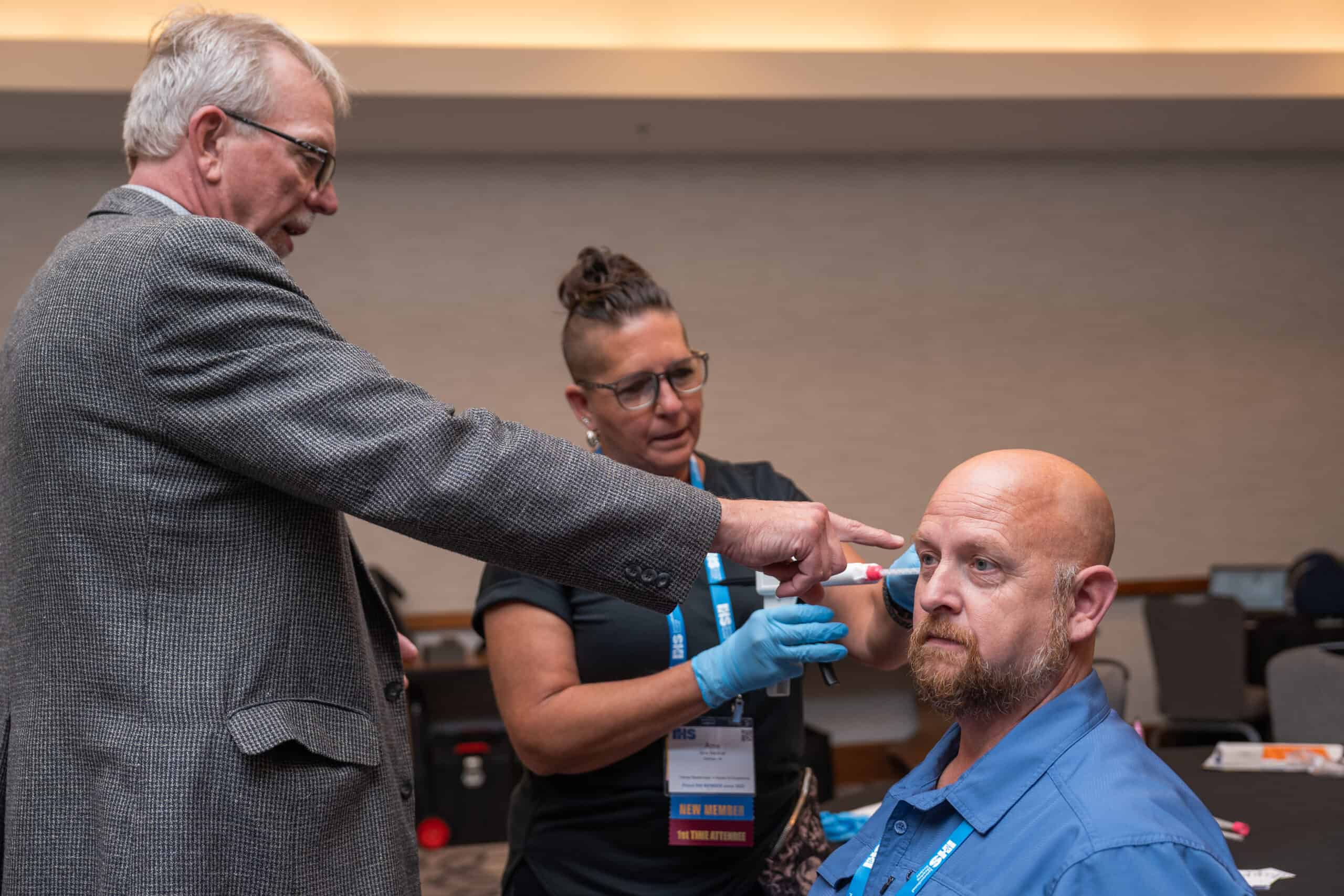 instructor and a trainee running through an injection mold exercise on a volunteer patient during the trainee masterclass at the IHS Conference & Expo