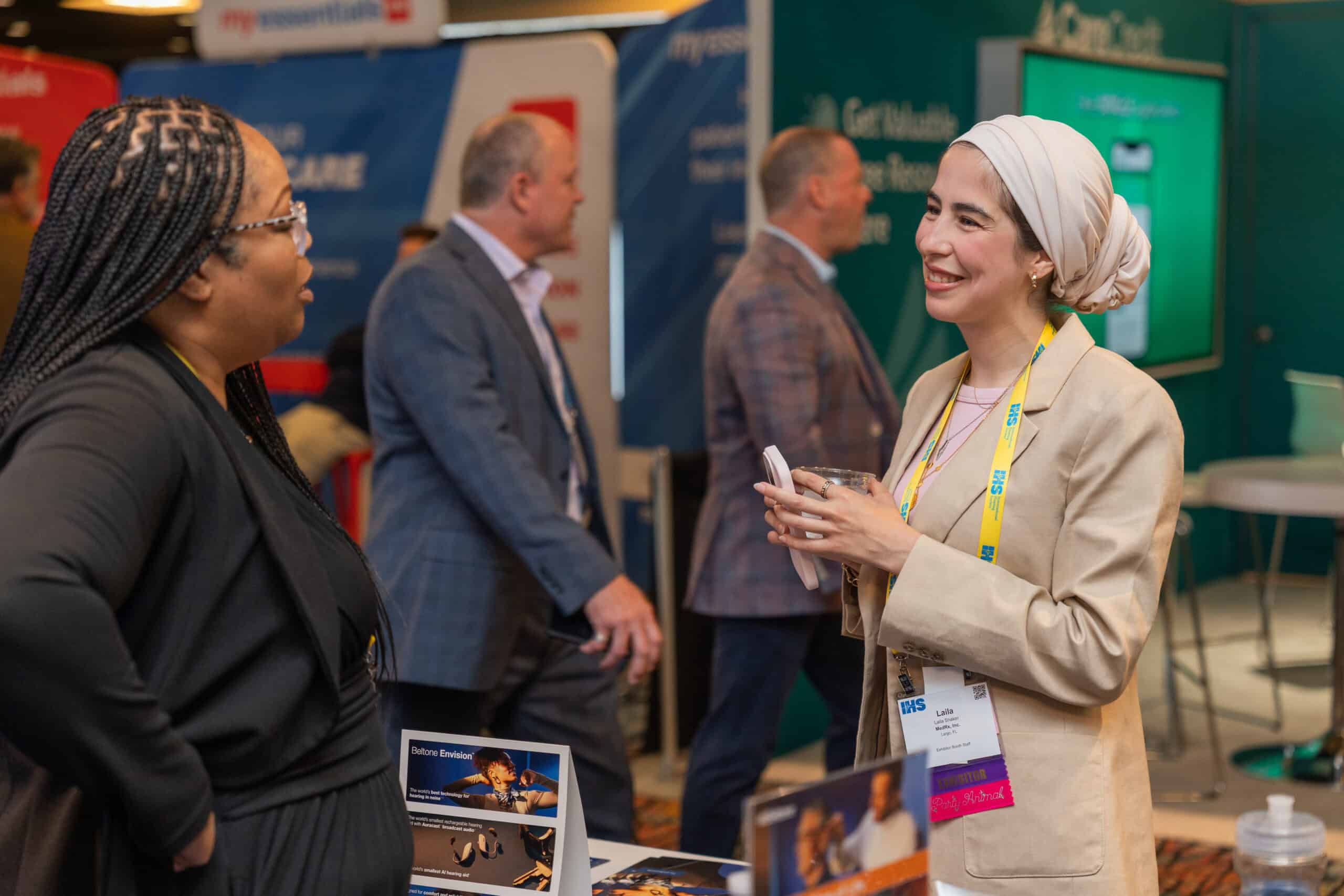two women smiling and speaking with each other during the Expo at the IHS Conference & Expo