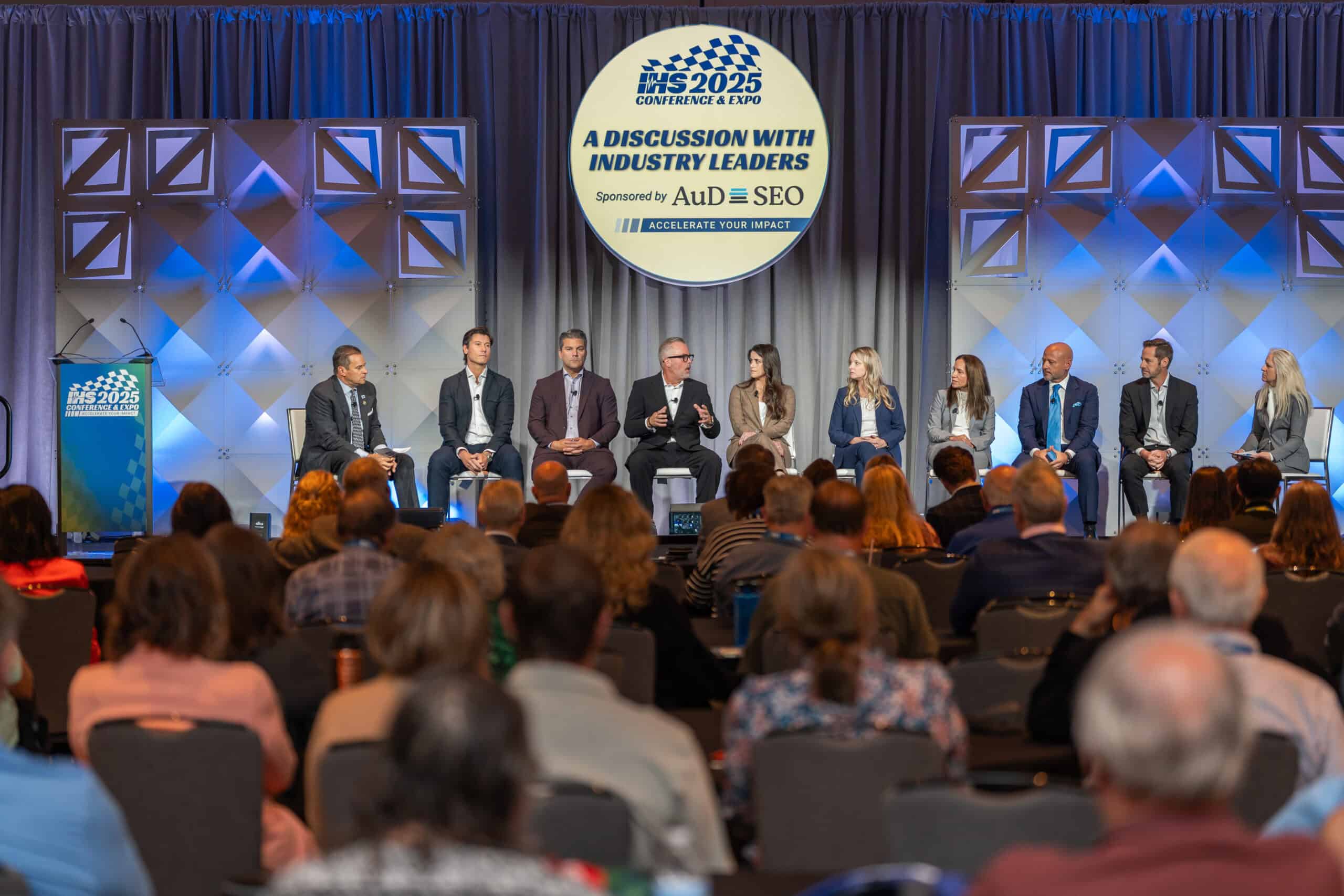 Panel of speakers talks on stage at a conference session.