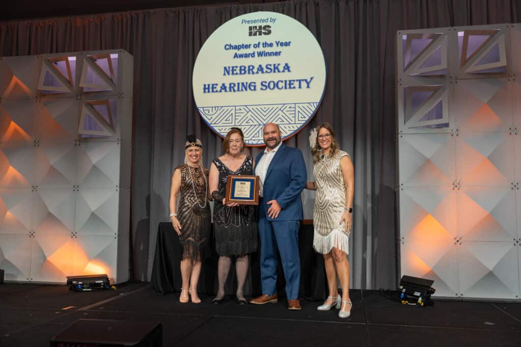 Members of the Nebraska Hearing Society accepting the 2025 Chapter of the Year Award on stage with Executive Director, Alissa Parady, CAE, and President-Elect, Leanne Polhill, BA, BC-HIS