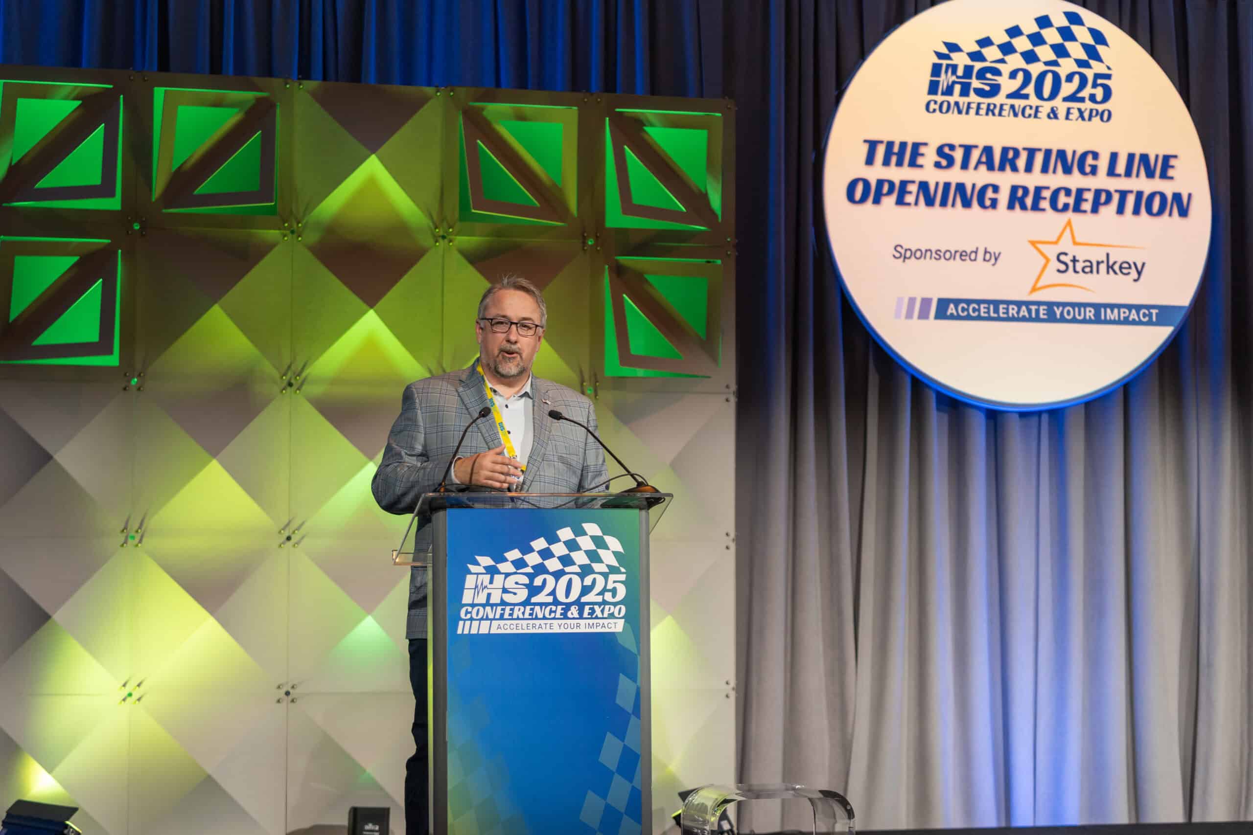 sponsor representative speaking in front of their sponsored event signage