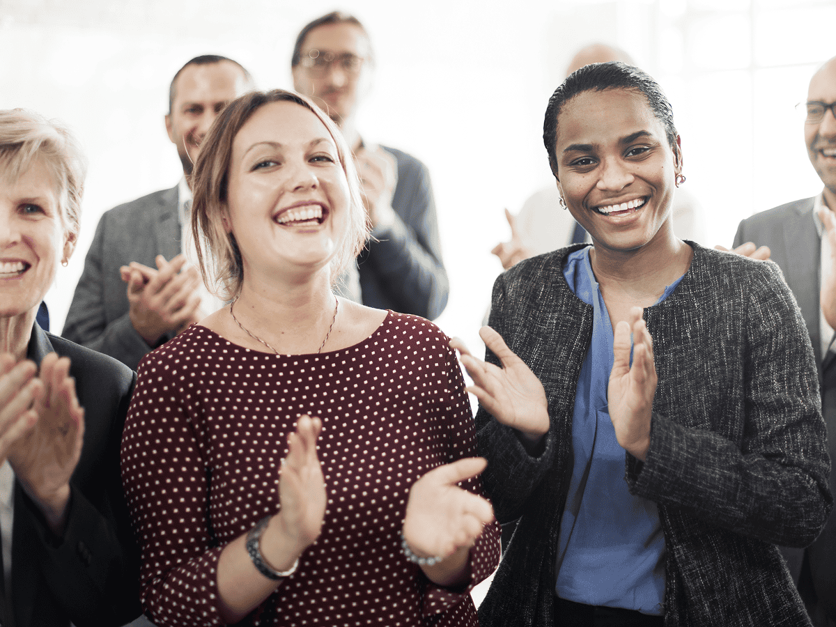 Group of colleagues smiling and clapping together.