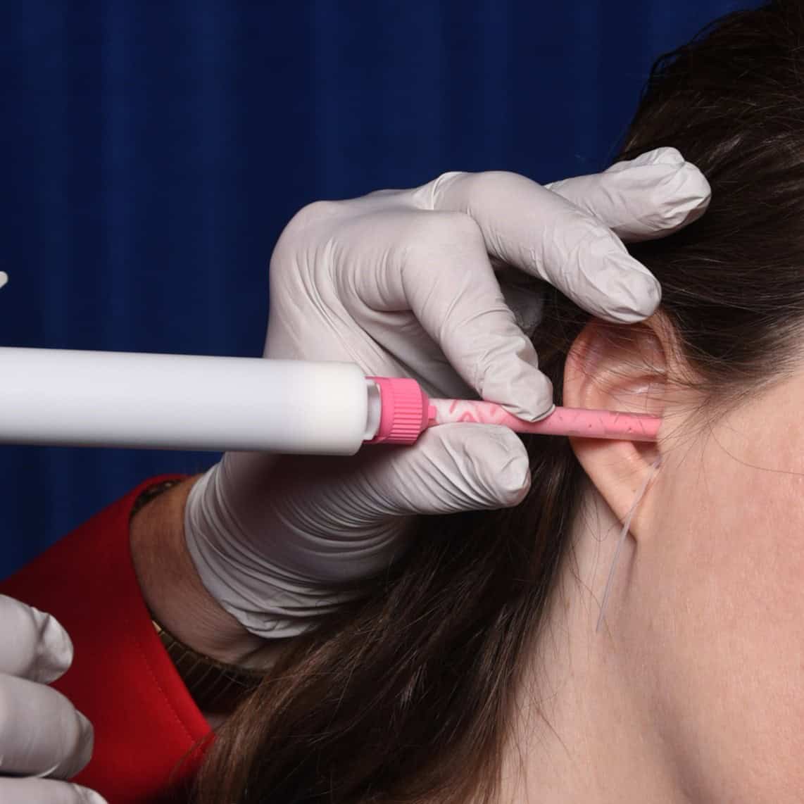 Medical professional administering ear injection with precision equipment.