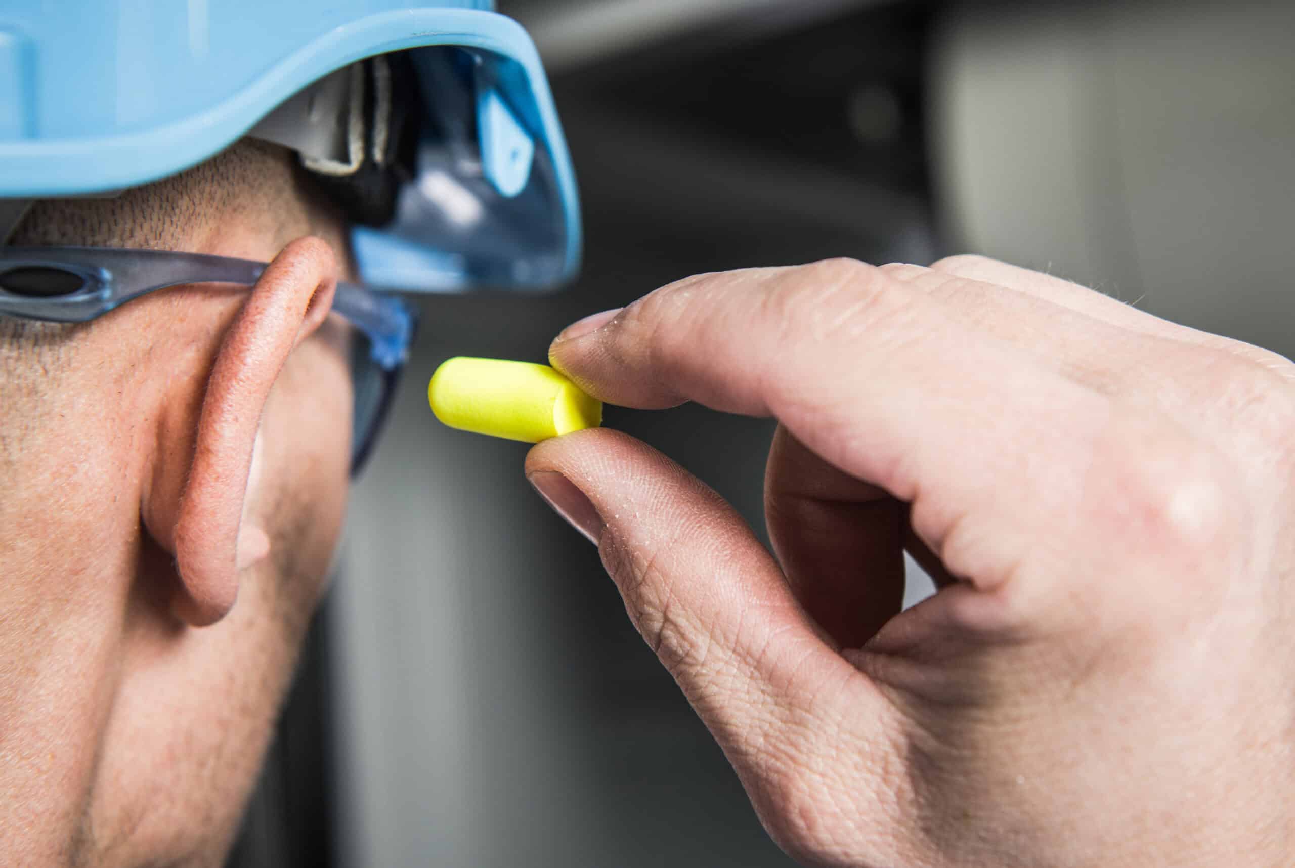 construction worker putting an earplug in their ear