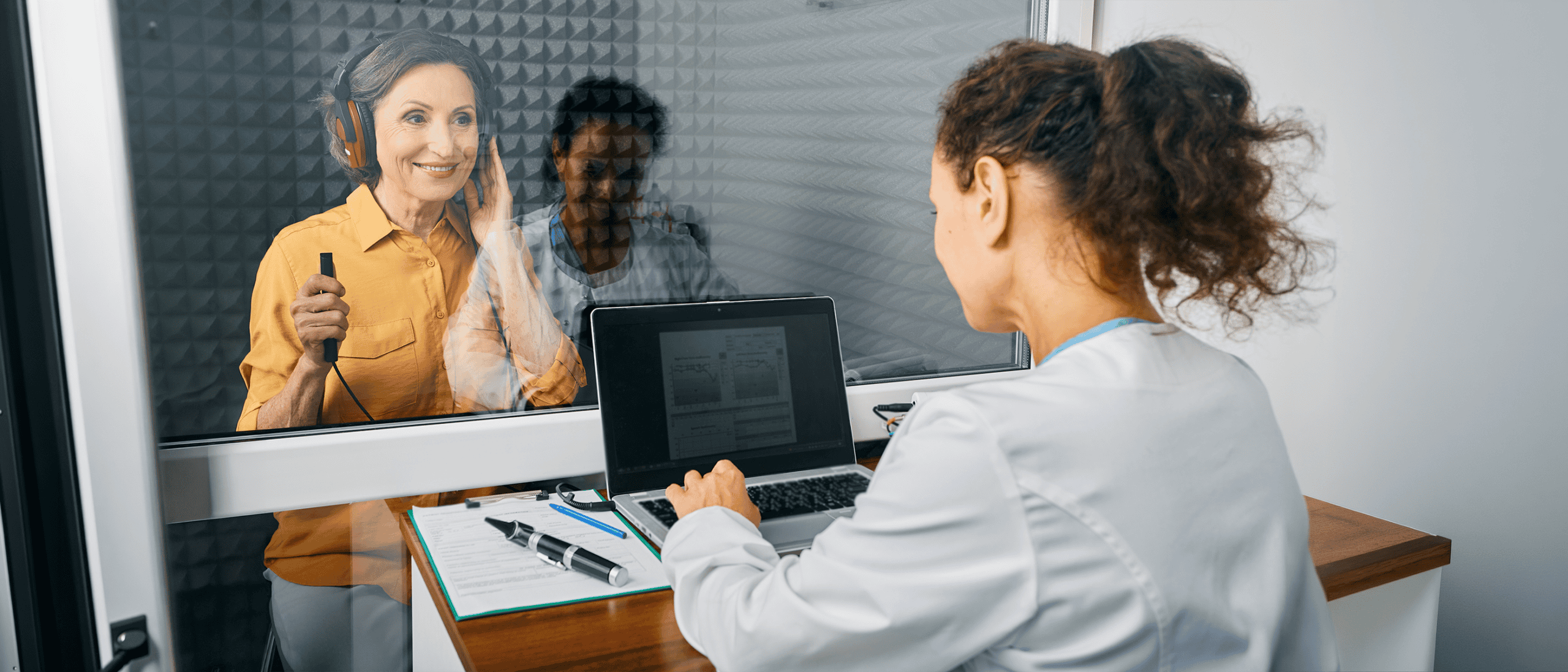 Woman wearing headphones completes a hearing test in a sound booth.