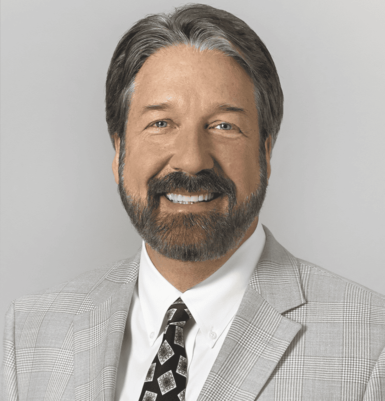 Bradley McMillin, ACA, BC-HIS wearing a plaid suit and tie