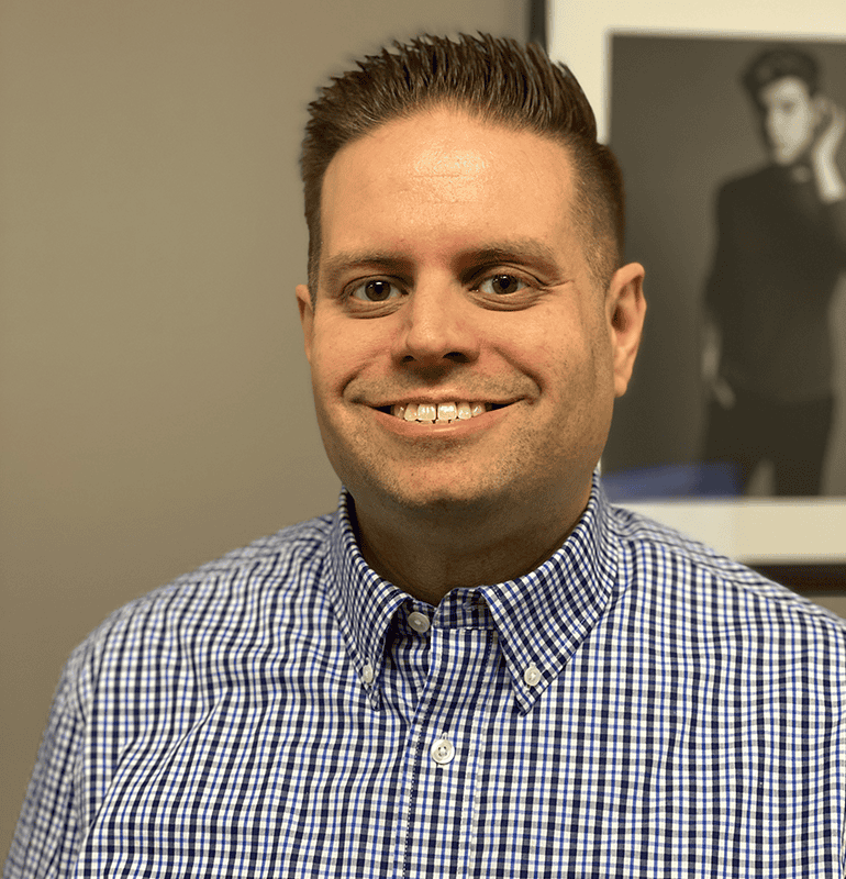 Chris Arnold in a blue checkered shirt smiling confidently at the camera.