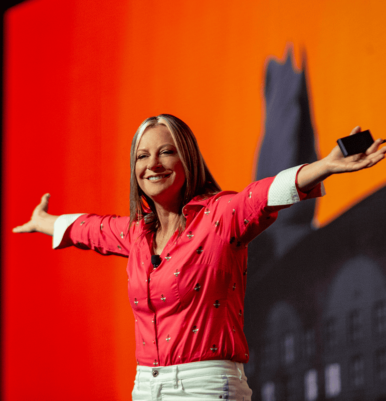 Dr. Michelle Rozen presenting with arms outstretched on stage at a conference.