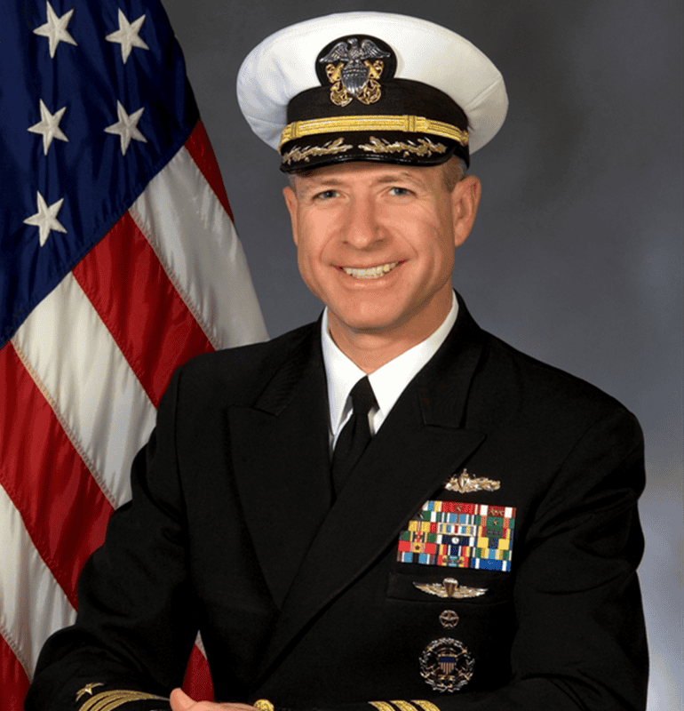 Commander Kirk S. Lippold, USN (Ret.), in uniform with US flag.