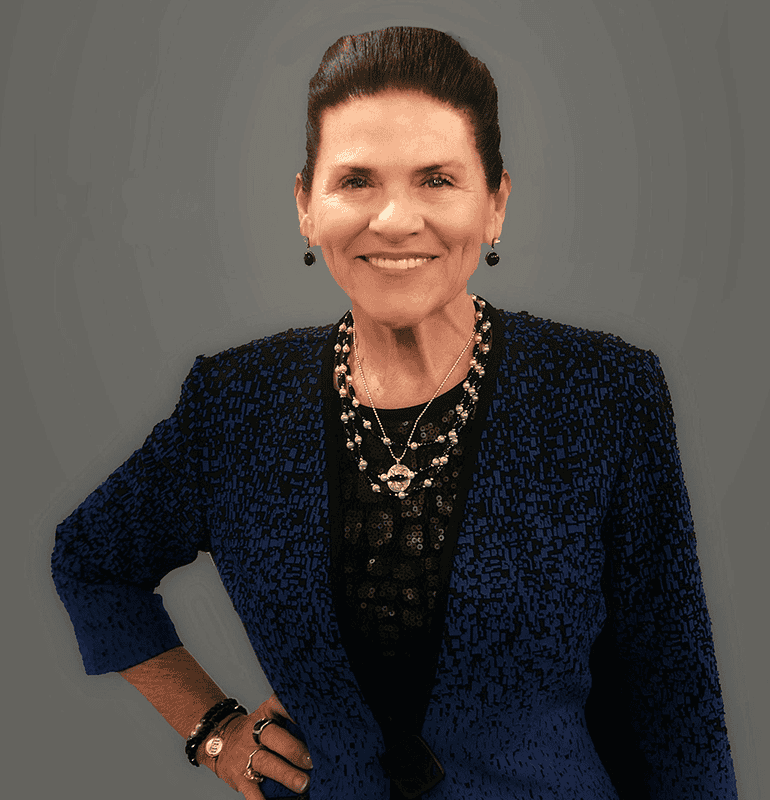 Tani Austin smiles in a blue jacket and jewelry, portrait shot.