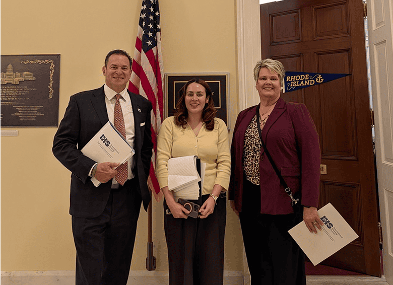 Three advocates on Capitol Hill with Rhode Island flag.