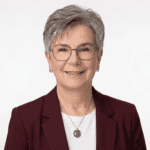 Professional headshot of a smiling woman with short gray hair.