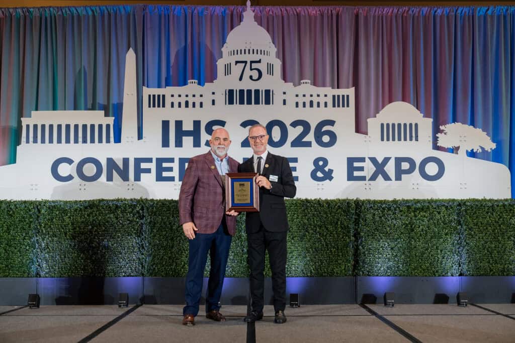 2025 James P. Lovell Advocacy Award Winner, Jason Winn, PA, accepting his award on stage with Executive Director, Alissa Parady, CAE, and President-Elect, Leanne Polhill, BA, BC-HIS