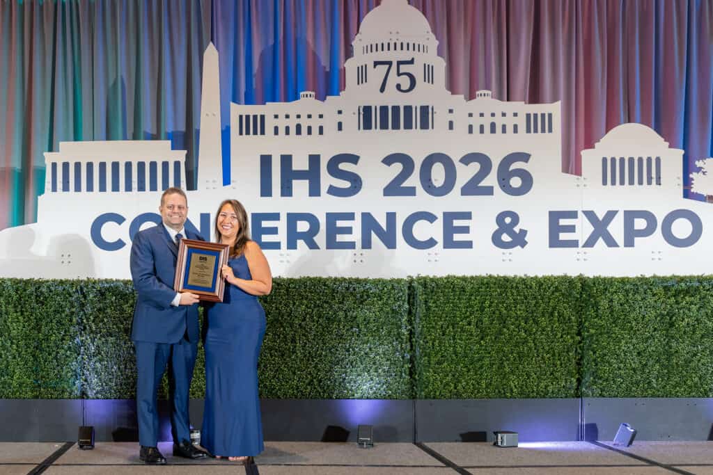 2025 Outstanding Professional Member Award Winner, Chris Arnold, accepting his award on stage with Executive Director, Alissa Parady, CAE, and President-Elect, Leanne Polhill, BA, BC-HIS