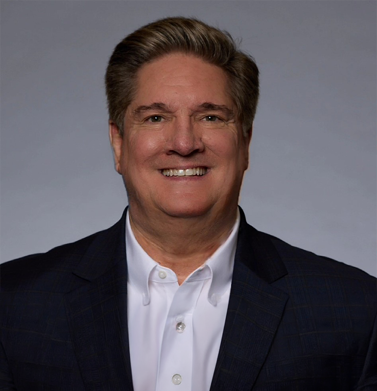 Tony Sulsona smiling in a dark suit and white shirt
